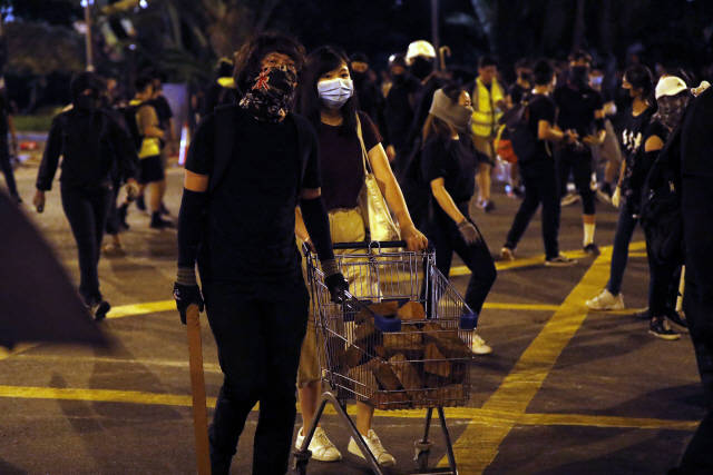 홍콩 정부가 지난 5일 0시부터 복면금지법을 시행한다고 발표한 날, 마스크를 한 홍콩의 시위자들이 벽돌을 채운 손수레를 끌고 거리를 이동하고 있다. / AP연합뉴스