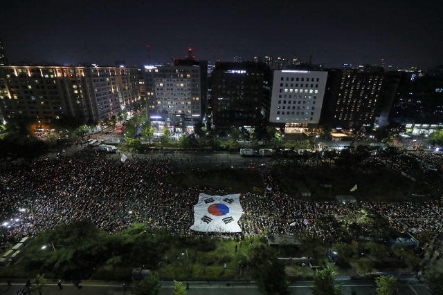 19일 저녁 서울 여의도 국회 앞에서 열린 ‘사법적폐청산을 위한 제10차 검찰개혁 촛불문화제’에서 참가자들이 태극기 퍼포먼스를 펼치고 있다. /연합뉴스