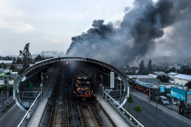 19일(현지시간) 화재가 발생한 칠레 산티아고 지하철역에서 검은 연기가 치솟고 있다. 세바스티안 피녜라 칠레 대통령은 이날 시위를 촉발한 지하철요금 인상을 중단할 것이라고 발표했다. /산티아고=AFP연합뉴스