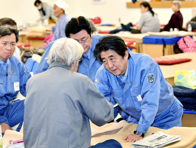 아베 신조 일본 총리가 지난 17일 후쿠시마현 모토미아시의 이재민 쉼터를 찾아 주민들을 위로하고 있다./후쿠시마=교도연합뉴스