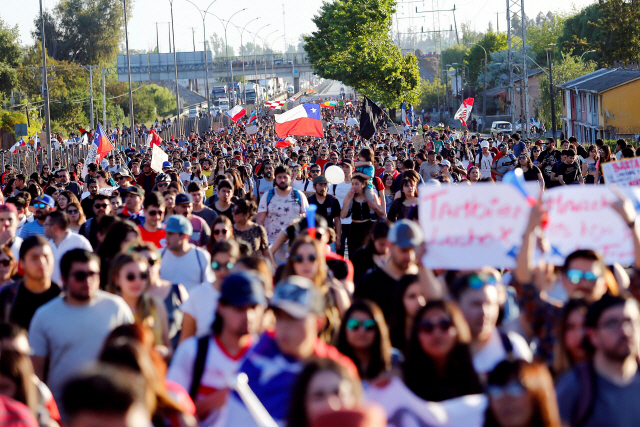 칠레의 반정부시위대가 23일(현지시간) 산티아고에서 국기를 들고 잦은 공공요금 인상과 높은 생활물가에 항의하고 있다./EPA연합뉴스