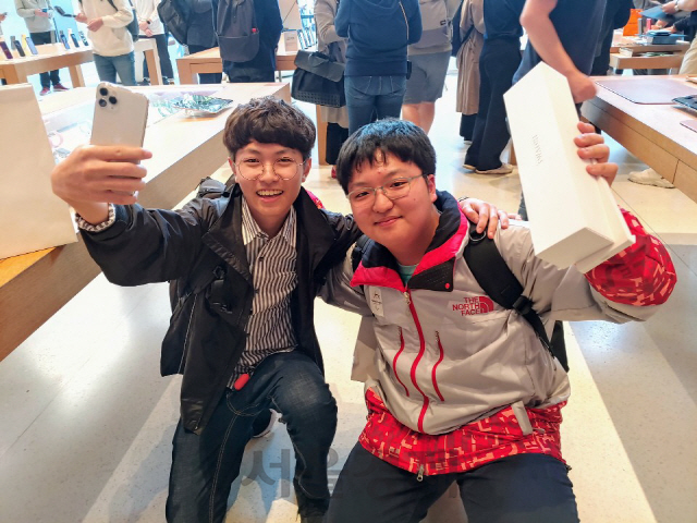 송영준(왼쪽)군과 백두연군이 25일 가장 먼저 아이폰11 시리즈와 애플워치5를 구입한 뒤 제품을 들어올려보이고 있다./권경원기자