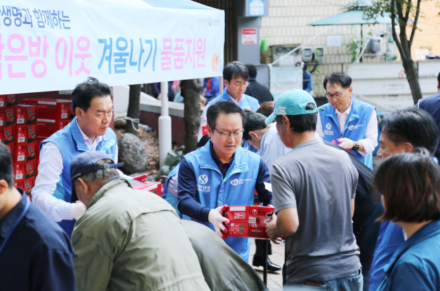 성대규(가운데) 신한생명 대표와 임원들이 지난 24일 서울역 쪽방상담소 나눔터에서 아나바다 행사 판매 수익금으로 구매한 라면 947상자를 쪽방촌 거주민들에게 전달하고 있다. /사진제공=신한생명