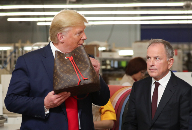 도널드 트럼프(왼쪽) 미국 대통령이 17일(현지시간) 텍사스주에 건설된 루이비통 공장을 방문해 마이클 버크 루이비통 최고경영자(CEO) 앞에서 루이비통 가방을 들어 보이고 있다.   /알바라도=로이터연합뉴스