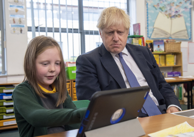 보리스 존슨(오른쪽) 영국 총리가 지난 25일(현지시간) 영국의 한 초등학교를 방문해 한 학생의 학습활동을 지켜보고 있다./AP연합뉴스