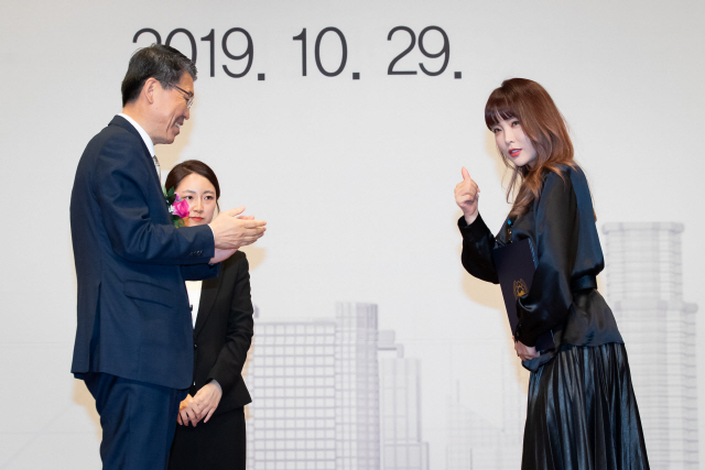 은성수(왼쪽) 금융위원장이 29일 서울 여의도 63빌딩에서 열린 ‘제4회 금융의 날’ 행사에서 국무총리 표창을 받은 가수 홍진영씨에게 상장을 준 후 박수를 치고 있다. /사진제공=금융위원회