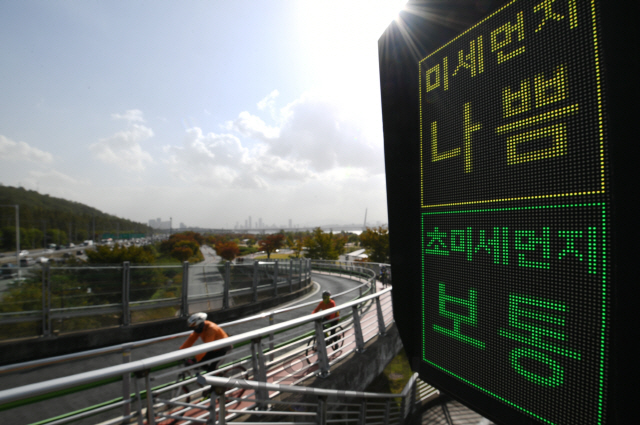 중국발 황사의 영향으로 미세먼지주의보가 내려진 29일 서울 마포구 난지 한강공원에서 시민들이 미세먼지 농도가 ‘나쁨’으로 표시된 ‘미세먼지 신호등’ 앞을 지나고 있다./오승현기자