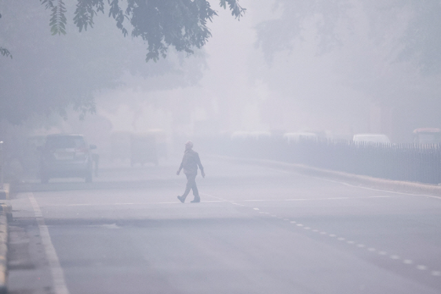 지난 4일(현지시간) 자동차 매연 등으로 앞이 잘 보이지 않는 인도 뉴델리 도르를 한 남자가 건너고 있다.  정도로 흐릿하다./AFP연합뉴스