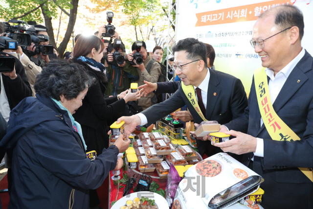 김현수(오른쪽에서 두번째) 농림축산식품부 장관이 8일 서울 여의도 국회도서관 앞에서 열린 농가보호를 위한 국내산 돼지고기 안전성 홍보 및 소비 촉진 행사에서 시민들에게 제품을 나눠주고 있다. 돼지고기 생산자와 소비자, 국회의원 등 각계가 참석해 아프리카돼지열병(ASF) 발생 후 소비가 줄어든 돼지고기의 소비를 끌어올리기 위해 삼겹살 등 인기 부위를 반값에 할인 판매했다. 이날 행사는 국회 농림축산식품해양수산위원회가 주최하고 농협 경제지주 주관으로 열렸다.