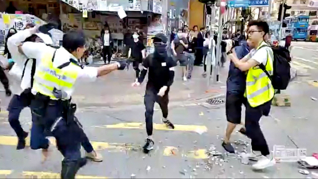 11일(현지시간) 오전 홍콩 사이완호 지역에서 열린 시위를 진압하던 경찰이 자신에게 접근하는 시위자를 향해 권총을 겨누고 있다.      /사이완호=로이터