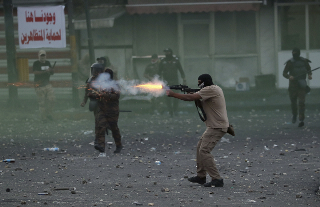 이라크 군경이 10일(현지시간) 이라크 수도 바그다드에서 반정부 시위대를 향해 최루탄을 발포하고 있다./바그다드=AP연합뉴스