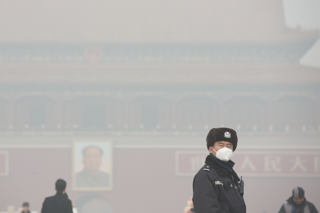 짙은 스모그 아래 중국 경찰이 베이징 톈안먼 광장에서 순찰을 돌고 있다. 경기둔화로 환경 규제가 느슨해지는 가운데 난방시즌이 겹치면서 올해도 겨울 대기질이 한층 악화될 것으로 우려된다.  /블룸버그