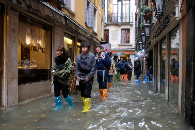 12일(현지시간) 이탈리아 베네치아에서 관광객들이 침수된 길을 걷고 있다./베네치아=로이터연합뉴스