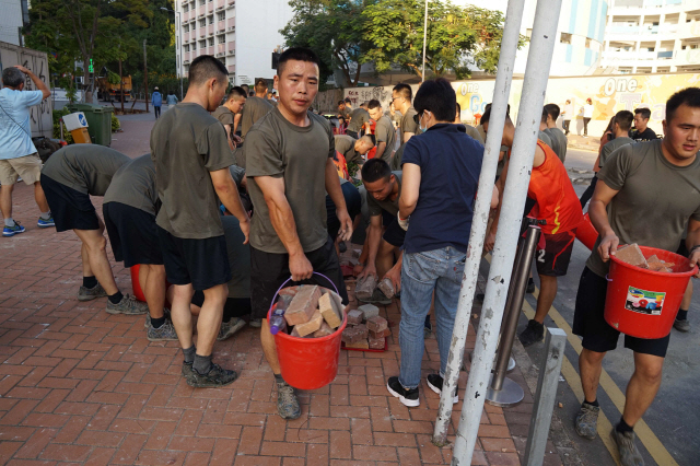 홍콩 주둔 중국군 병사들이 16일 시위대가 남겨놓은 벽돌을 치우고 있다. /AFP연합뉴스