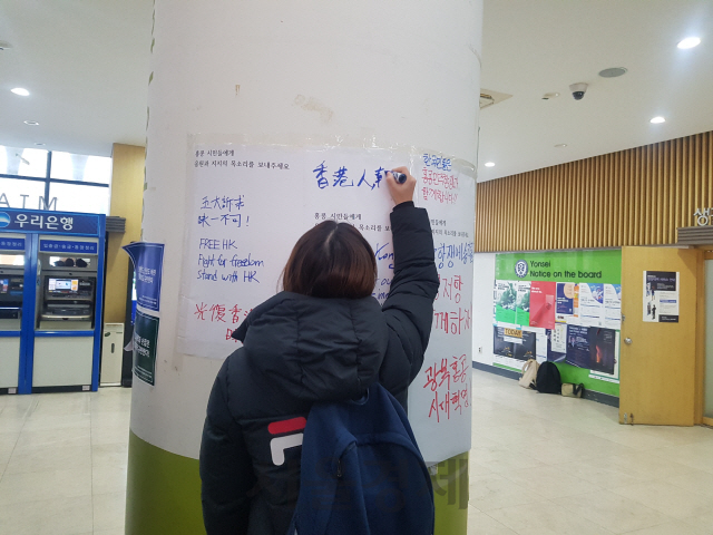 18일 서울 서대문구 연세대학교 학생회관에 설치된 ‘레넌 벽’에 한 학생이 홍콩의 시위를 지지하는 메시지를 적고 있다./김지영 기자