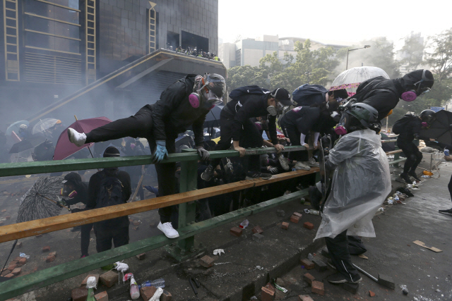 시위자들이 18일 아침 홍콩대 이공계 교정에서 경찰과 충돌하는 과정에서 담을 넘고 있다./AP=연합뉴스