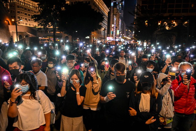 19일 홍콩 시민들이 홍콩이공대 인근 침사추이 지역의 솔즈베리 가든에 모여 휴대전화 불빛을 밝힌 채 홍콩이공대 안에 남아 있는 시위대를 위해 기도하고 있다./홍콩=AFP연합뉴스