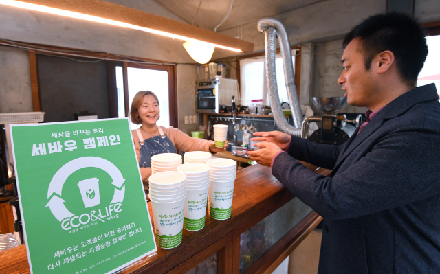 세바우 캠페인 참여 카페를 방문한 한 시민이 세바우 컵에 담긴 음료를 전달받고 있다./권욱기자