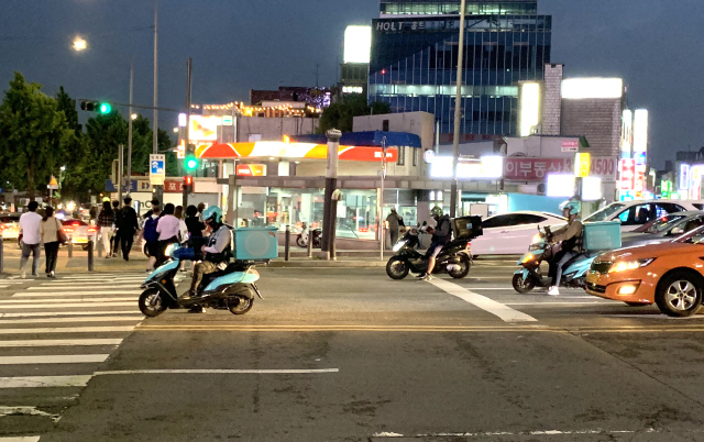 배달대행 업체의 음식배달원들이 오토바이를 타고 이동 중 신호를 기다리고 있다. /강신우기자