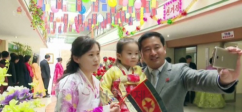 북한은 지난 3월 10일 남한의 국회의원 총선거에 해당하는 제14기 최고인민회의 대의원 선거 투표를 진행했다. 사진은 투표소에 나온 북한의 한 가족이 휴대폰으로 기념사진을 찍고 있는 모습./연합뉴스
