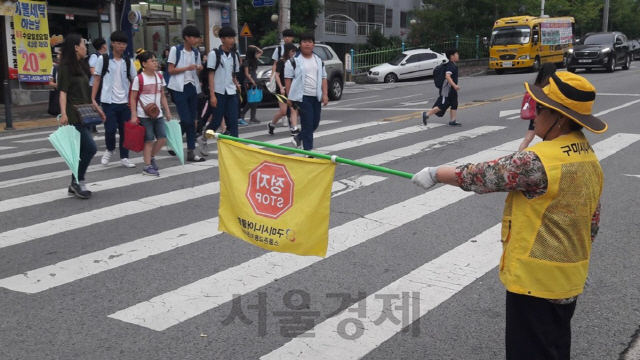 노인 일자리 사업에 참여한 한 어르신(오른쪽)이 학생들의 등교 시간에 교통 정리를 하고 있다./사진 = 구미시 제공