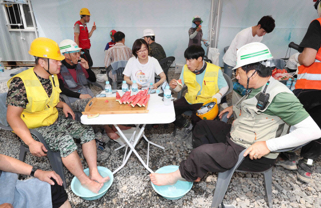 서울 강동구의 한 건설현장에서 근로자들이 폭염을 피해 그늘에서 수박을 먹으며 휴식을 취하고 있다. /연합뉴스