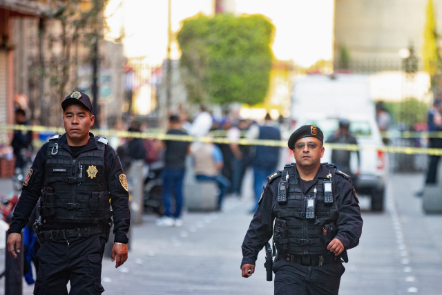 7일(현지시간) 대낮에 총격이 발생한 멕시코 수도 멕시코시티 도심 대통령궁 근처를 경찰들이 폴리스라인을 치고 순찰하고 있다. 멕시코시티=로이터연합뉴스