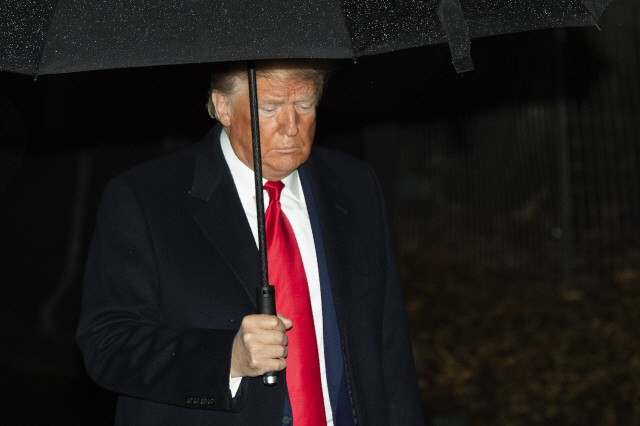 도널드 트럼프 미국 대통령이 10일(현지시간) 백악관 집무실에서 나와 우산을 쓴 채 걷고 있다./워싱턴 AP=연합뉴스
