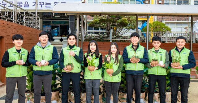 현대위아 직원들이 19일 ‘현대위아 초록학교’로 꼽힌 경남 창원시 남양초등학교에서 교실숲을 만들 화분을 들고 기념사진을 찍고 있다./사진제공=현대위아