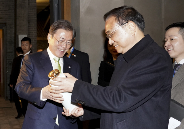 문재인 대통령이 지난 23일 오후 중국 쓰촨성 청두 수정방박물관을 방문해 리커창 중국 총리로부터 특별제작된 백주를 선물받고 있다./연합뉴스