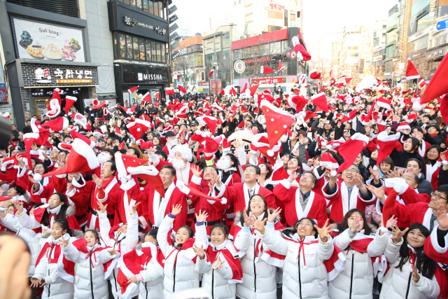 24일 서울 신촌 연세로에서 올해 ‘몰래 산타’들이 선물을 나눠주기 전 산타 모자를 던지면서 웃고 있다. / 사진제공=중기부