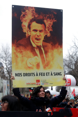 지난 9일(현지시간) 프랑스 파리에서 한 시위 참가자가 에마뉘엘 마크롱 대통령을 비판하는 글판을 들고 있다. /파리=로이터연합뉴스