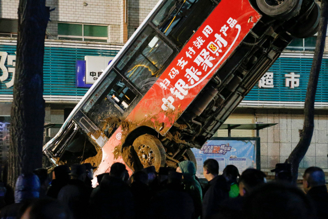 13일(현지시간) 중국 칭하이성 시닝시의 도로 함몰 사고 현장에서 구조대원들이 추락한 버스를 끌어올리고 있다. /시닝=AFP연합뉴스