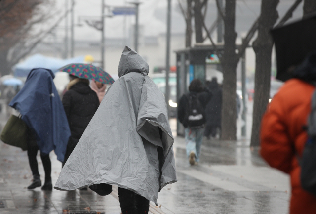 눈이 내리다 비가 오는 19일 오후 우비를 입은 시민들이 서울 광화문광장 인근을 지나고 있다./연합뉴스