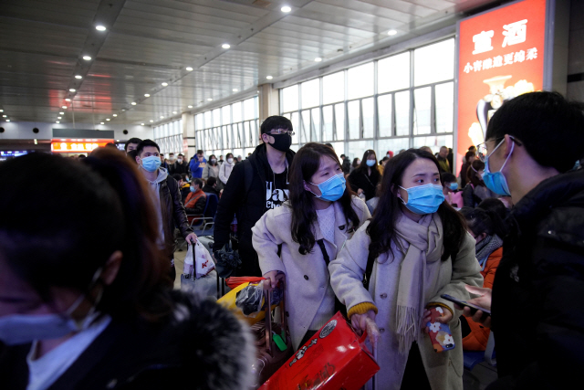 중국 최대 명절인 춘제를 앞둔 22일(현지시간) 중국 상하이 기차역에서 마스크를 쓴 여행객들이 고향으로 가기 위해 탑승구로 향하고 있다./상하이=로이터연합뉴스