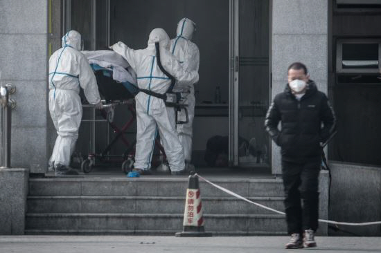 신종 코로나바이러스로 인한 ‘우한 폐렴’이 발생한 중국 후베이성 우한에서 지난 18일 의료진이 폐렴 환자들을 집중 치료하고 있는 한 병원으로 환자를 옮기고 있다./AFP=연합뉴스