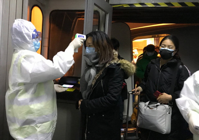 중국 베이징 공항에서 방호복을 입은 검역관이 22일 신종 코로나바이러스가 시작된 우한에서 출발해 들어오는 승객들의 체온을 측정하고 있다./베이징=AP연합뉴스