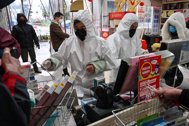 우한 폐렴인 신종 코로나바이러스 발원지인 중국 후베이성 우한의 약국에서 직원들이 25일(현지시간) 마스크를 착용한 채 근무를 하고 있다. /우한=AFP연합뉴스