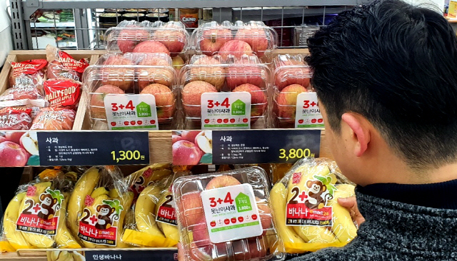 이마트24를 찾은 고객이 초특가 사과와 바나나 상품을 살펴보고 있다. /사진제공=이마트24