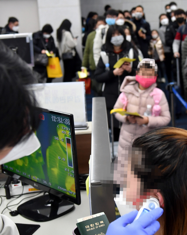 중국에서 부산 김해공항으로 입국한 승객들이 지난 28일 항공기 게이트 입구에서 발열 감시 및 체온 측정 조사를 받고 있다. /연합뉴스