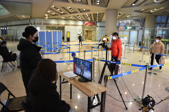 29일(현지시간) 중국 베이징 국제공항에서 공항 직원들이 입국자의 체온을 측정하고 있다./베이징=신화연합뉴스