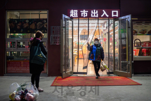 중국 베이징에서 마스크를 쓴 한 시민이 슈퍼마켓 밖으로 나오고 있다./베이징=AFP연합뉴스