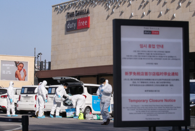 신종 코로나바이러스 감염증 확진자 방문이 확인됨에 따라 2일부터 임시 휴업에 들어간 신라면세점 서울점에서 3일 오후 방역업체 관계자들이 추가 방역작업을 위해 면세점 내부로 들어가기 위해 준비하고 있다. /연합뉴스