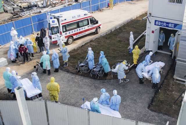 신종 코로나바이러스가 집중적으로 발생하고 있는 중국 우한에서 방호복을 입은 의료진이 4일(현지시간) 일부 환자들을 최근 완공된 훠선산 병원으로 이송하고 있다. /우한=AP연합뉴스