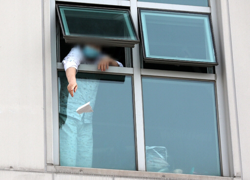 6일 오후 광주 광산구 광주21세기병원에서 3층에 격리된 환자가 쪽지를 창문 밖으로 던지고 있다./연합뉴스