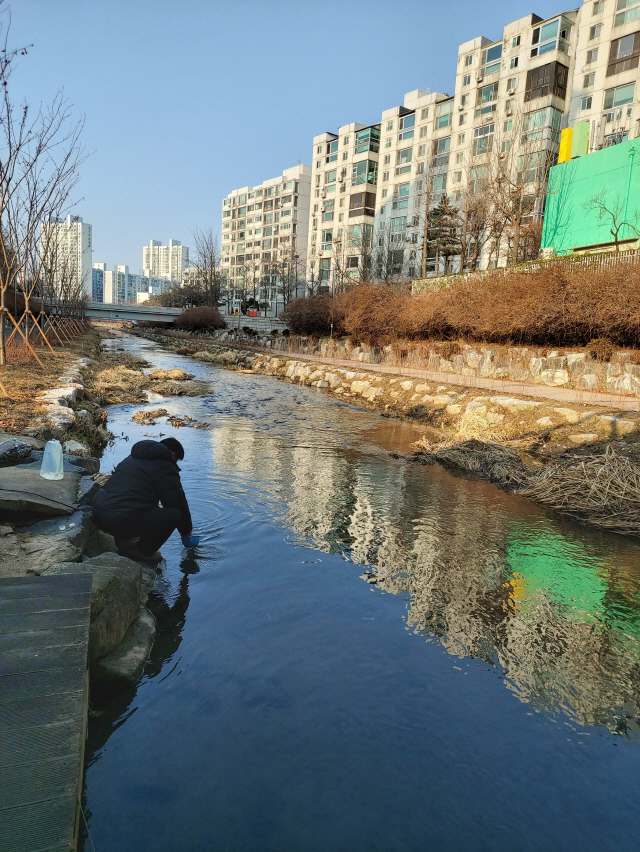 서울 송파구 공무원이 지역 하천의 수질 오염을 조사하기 위해 물을 뜨고 있다.    /사진제공=송파구