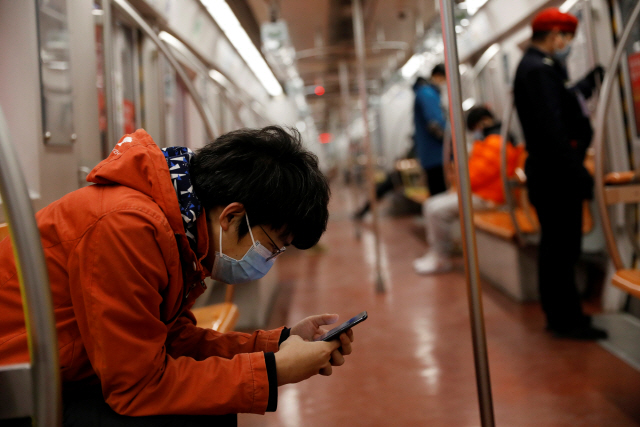 10일(현지시간) 중국 베이징에서 지하철을 탄 한 시민이 마스크를 쓴 채 스마트폰을 들여다보고 있다. /베이징=로이터연합뉴스