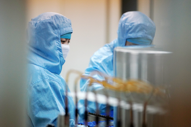 중국 헤이룽장성 하얼빈의 제약회사 공장에서 12일(현지시간) 코로나19 감염을 막기 위해 방호복과 마스크를 착용한 근로자들이 의약품을 나르고 있다.  /하얼빈=신화연합뉴스