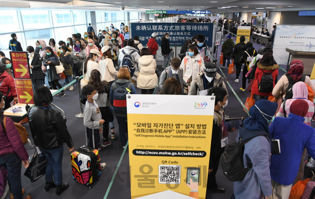 중앙사고수습본부가 홍콩과 마카오에서 입국하는 여행객에 대해서도 전수 검역조치를 결정한 가운데 13일 인천국제공항을 통해 홍콩에서 입국하는 여행객들이 '자가진단앱'을 설치하기 위해 줄을 서 있다./영종도=공항사진기자단