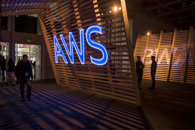 Attendees walk past a signage for Amazon Web Services (AWS) Summit in San Francisco, California, U.S., on Wednesday, April 19, 2017. Amazon.com Inc. Web Services chief executive officer Andy Jassy is leading a push into artificial intelligence to boost Amazon‘s cloud computing, which commands about 45 percent of the market for infrastructure as a service, where companies buy basic computing and storage power from the cloud. Photographer: David Paul Morris/Bloomberg